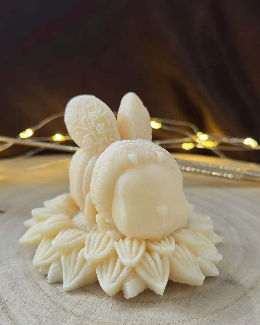 Ivory bee candle with patterned wings sitting on a ring of carved petals