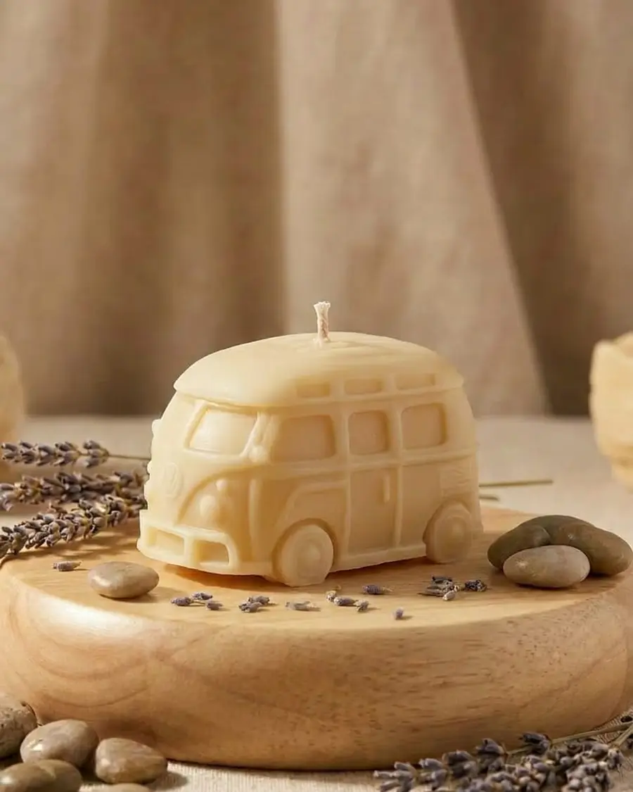 Natural wax camper van candle on a wooden board with pebbles and lavender
