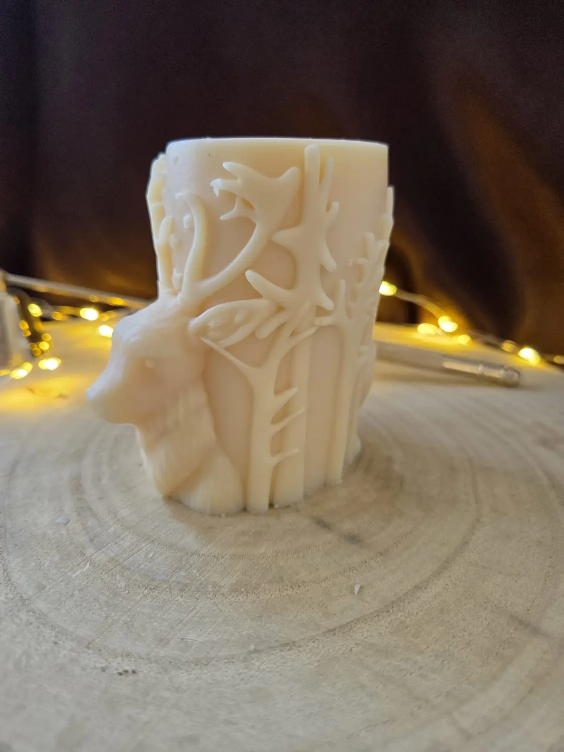 Ivory pillar candle carved with a Christmas tree, stars and a present