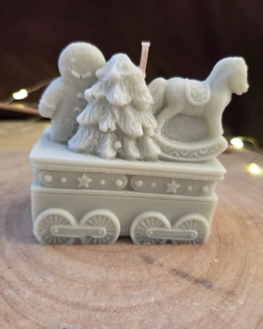 Train carriage candle carrying a Christmas tree, a gingerbread man and a rocking horse