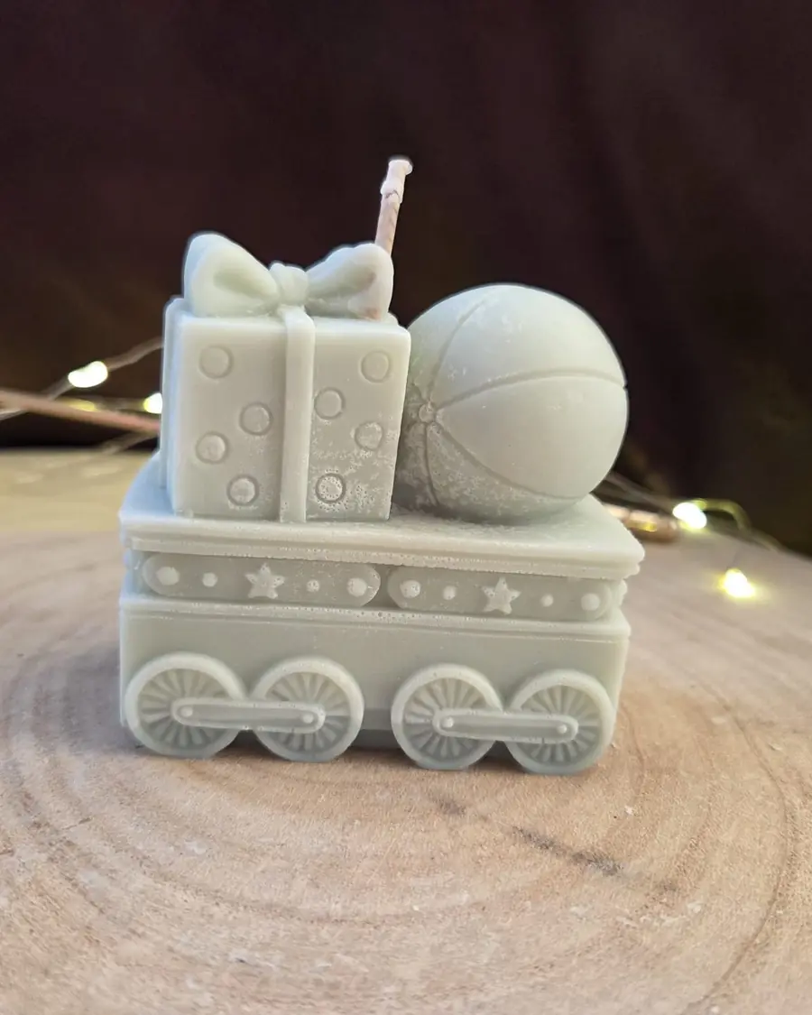 Train carriage candle carrying a wrapped present and a ball