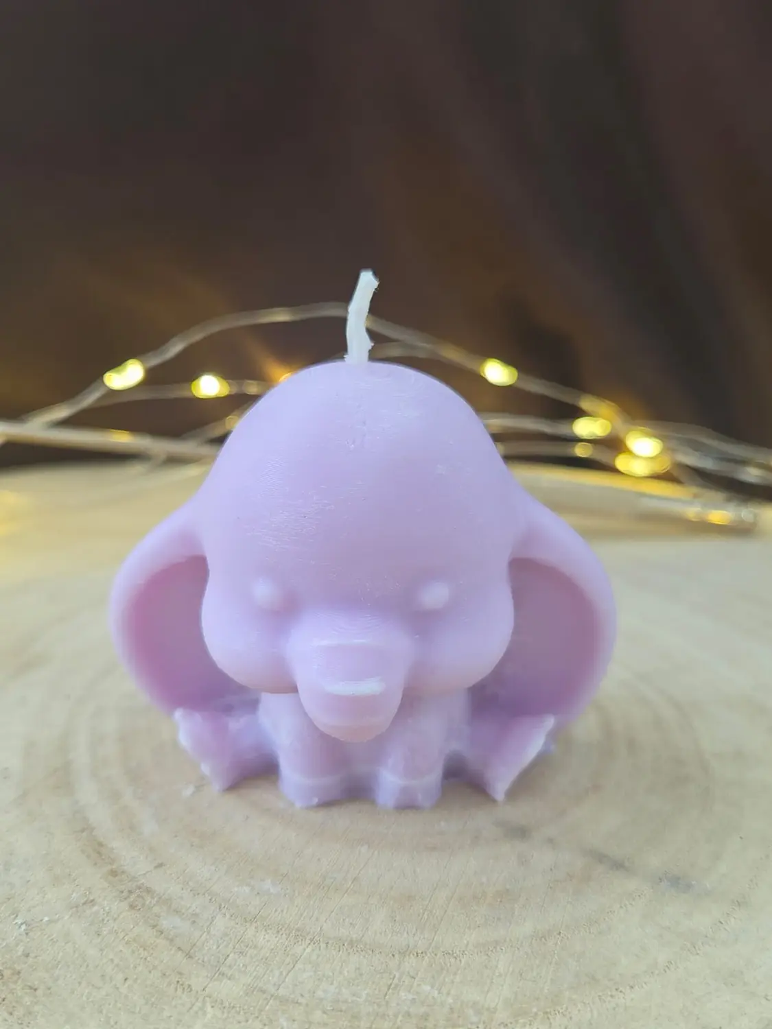 Lilac baby elephant candle with big ears, on a wood slice with fairy lights