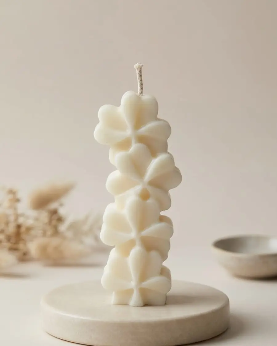 Ivory stacked candle of clover-shaped flowers on a stone dish