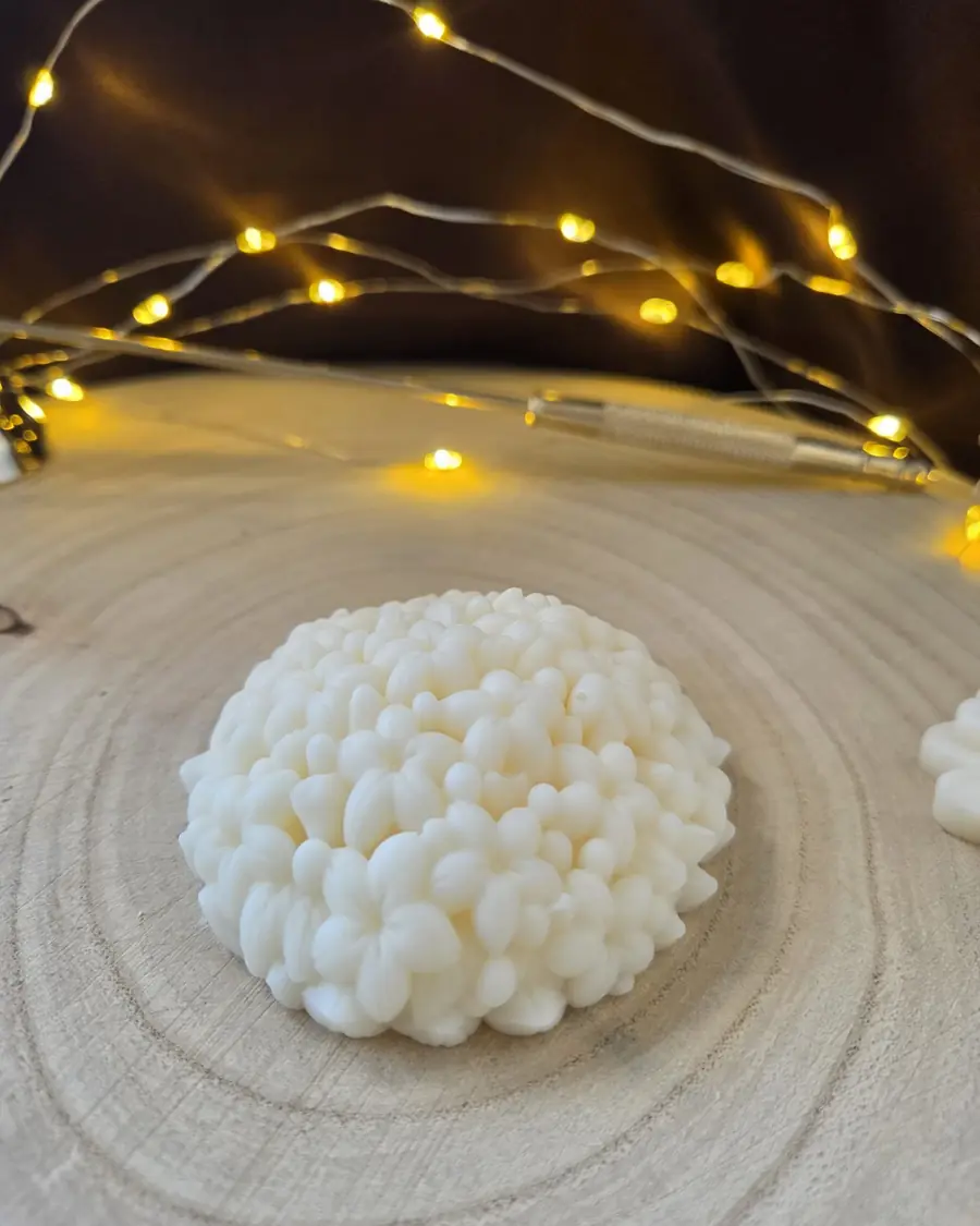 Ivory candle shaped like a dome of tiny flowers, on a wood slice