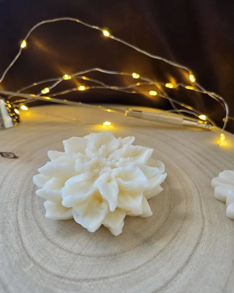 Ivory candle shaped like a layered open flower, on a wood slice