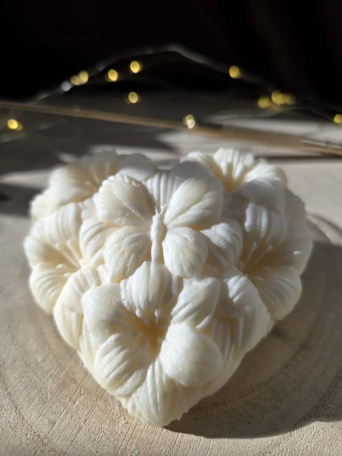 Ivory heart candle made of moulded flowers with a butterfly, in low sunlight