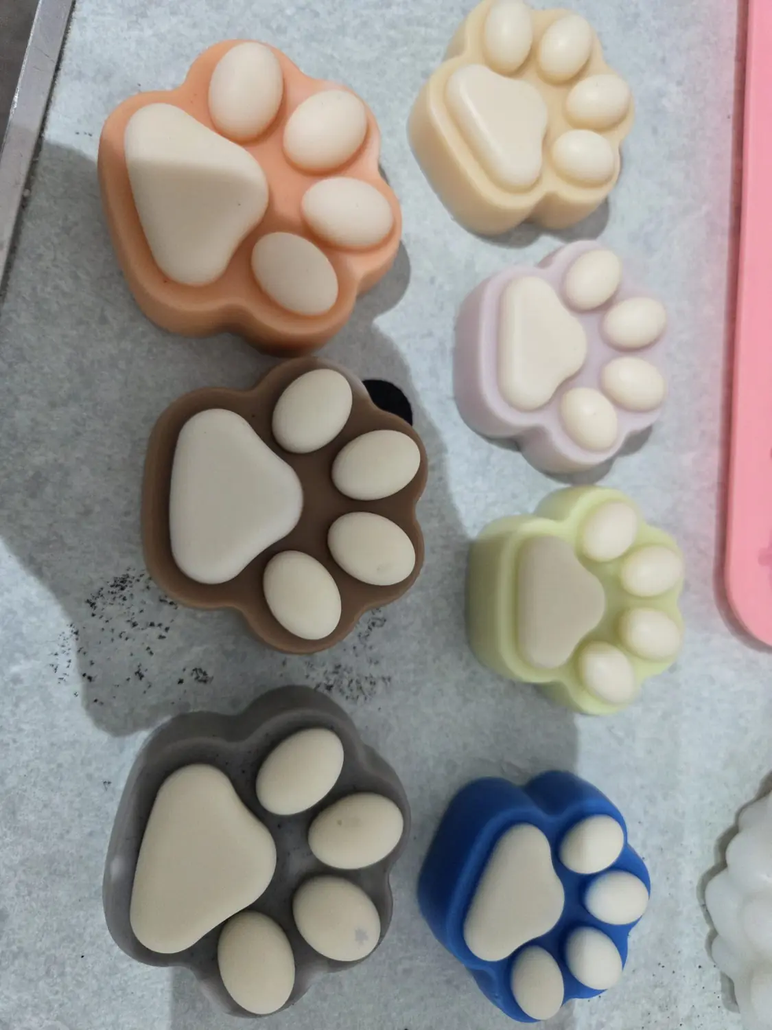 Paw print candles in peach, cream, lilac, brown, green, grey and blue