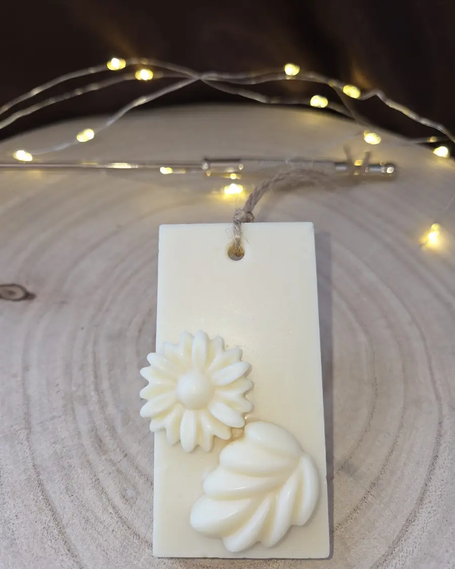 Ivory wax tablet with a daisy and a leaf, hanging from a twine loop