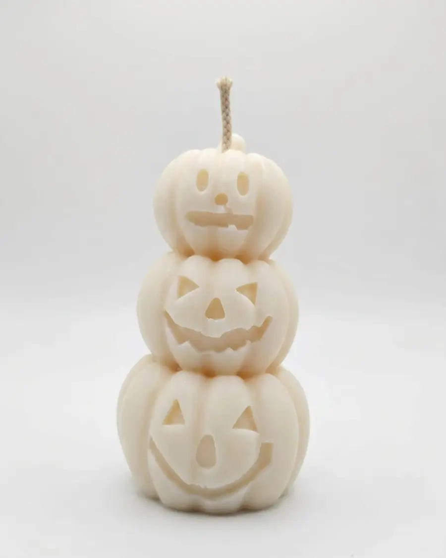 Ivory candle of three stacked jack-o'-lantern pumpkins on a white background