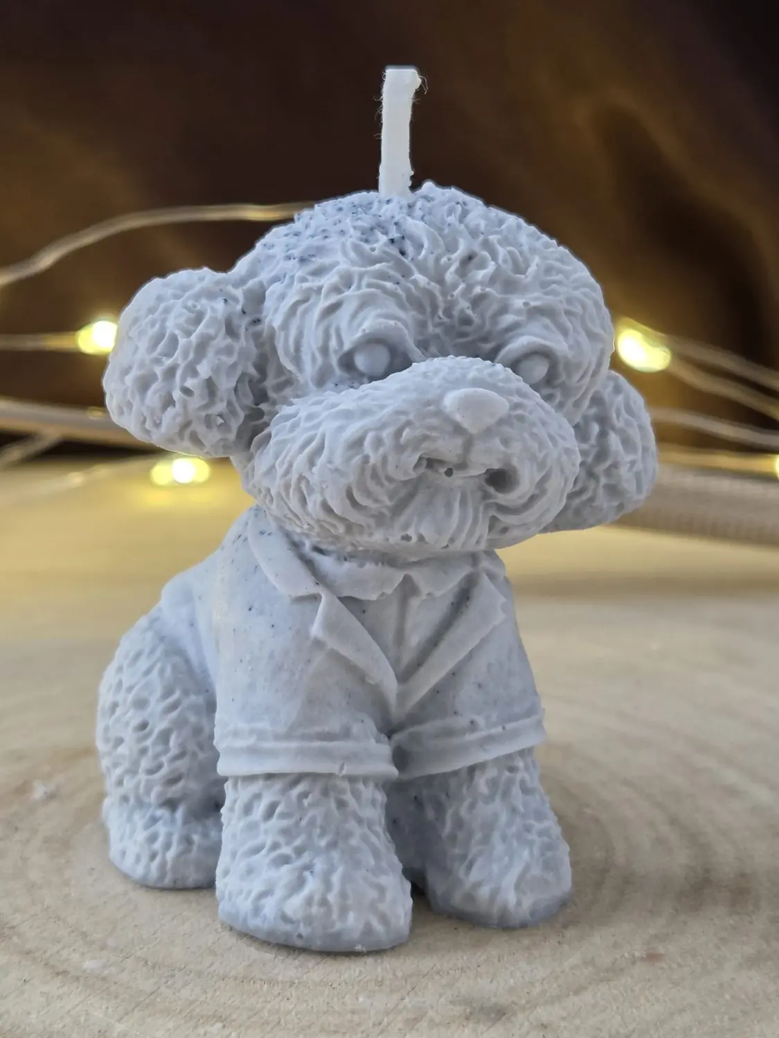 Grey blue curly-coated puppy candle wearing a collared shirt, on a wood slice