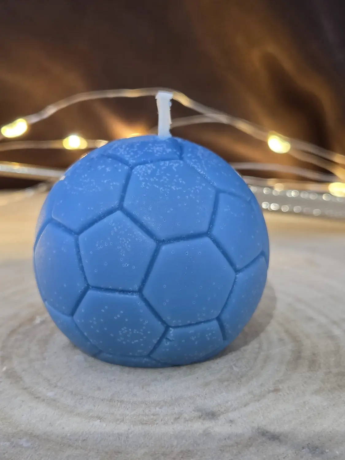 Blue football candle on a wood slice with fairy lights