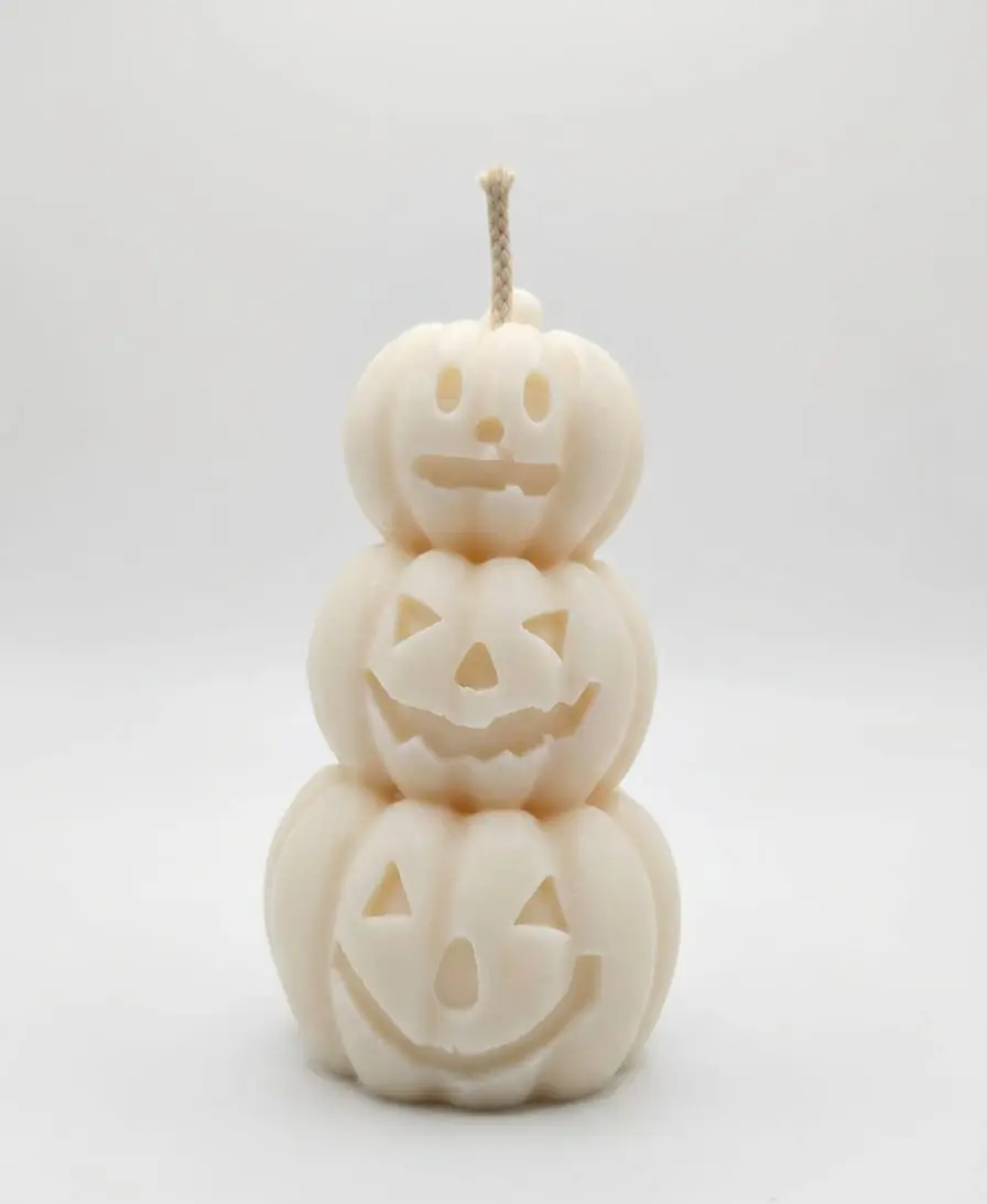 Ivory candle of three stacked jack-o'-lantern pumpkins on a white background